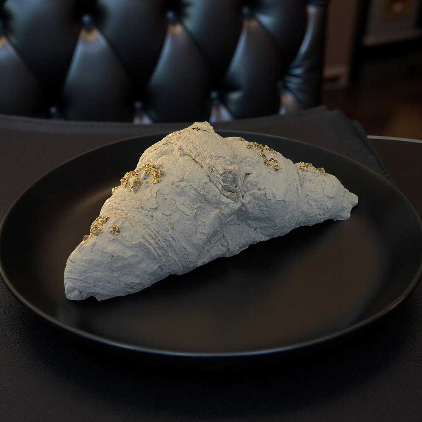 Handgemachtes Deko-Croissant aus Gießpulver, detailreich geformt, auf schwarzem Teller liegend - inspiriert vom französischen Frühstück